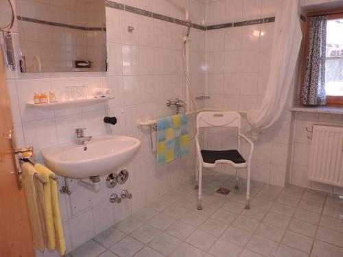 a bathroom with a sink and a chair in it at Ferienwohnungen Thomafischer in Chieming