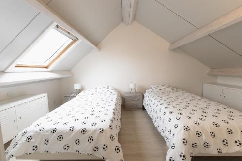 two beds in a attic bedroom with a window at Boszicht 32 in De Haan