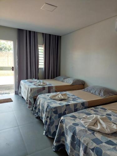 a hotel room with three beds and a window at Suíte Big Família - Queens Hotel in Formosa