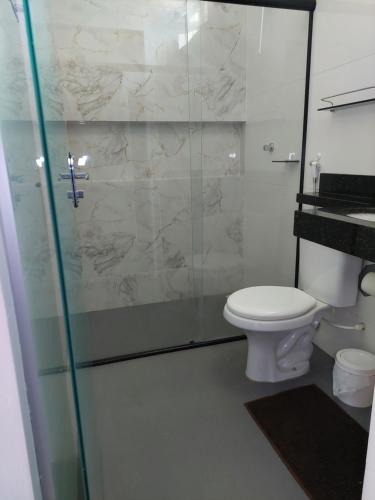 a bathroom with a toilet and a glass shower at Suíte Big Família - Queens Hotel in Formosa
