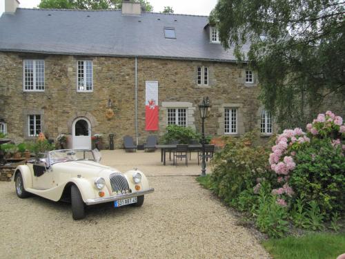 an old white car parked in front of a building at Manoir Desnachez in Taupont