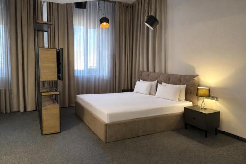 a hotel room with a bed and a television at Deribas Hotel in Odesa