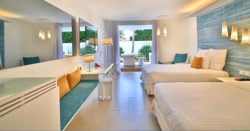 a hotel room with two beds and a desk at La Creole Beach Hotel & Spa in Le Gosier