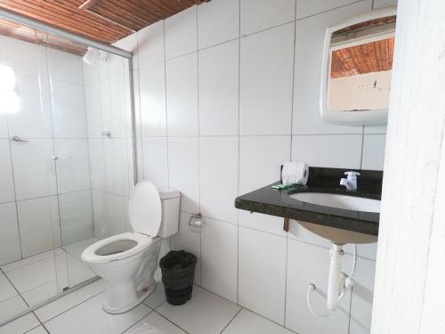 a white bathroom with a toilet and a sink at Pousada Terra Nostra in Prado