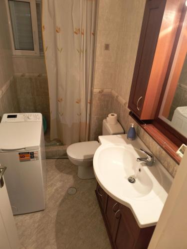 a bathroom with a white sink and a toilet at Big Terrace 180 view to sea in Akritokhórion