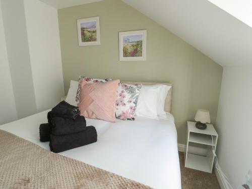 a bedroom with a bed with white sheets and pillows at Hen Siop in Llanfairpwllgwyngyll