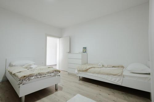 two beds in a bedroom with white walls and wooden floors at Guest house Ivan in Međugorje