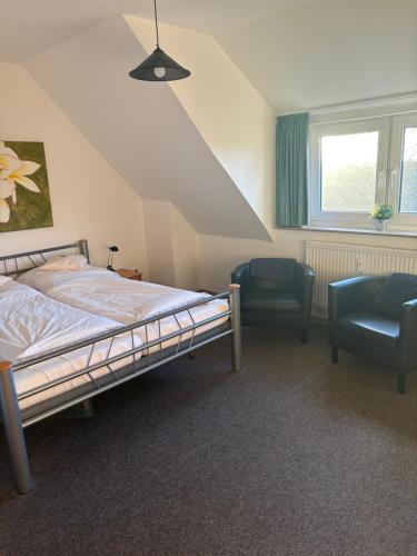 a bedroom with a bed and a chair and a window at Hotel Tristan Grün in Rheine