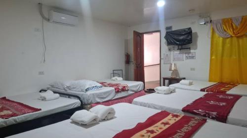 a room with three beds with towels on them at Knights-Apple Inn in Mambajao