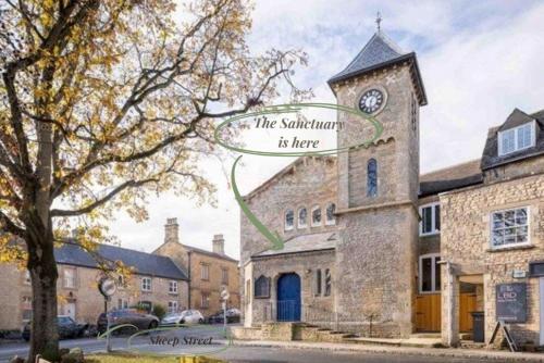 a building with a clock tower with a sign on it at The Sanctuary in Stow on the Wold