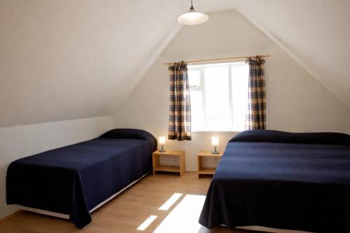 a attic bedroom with two beds and a window at Eystri-Solheimar in Vík