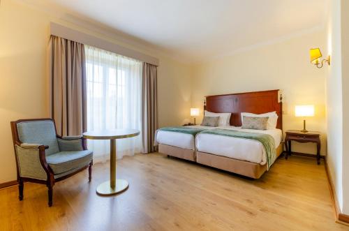 a bedroom with a bed and a table and a chair at Turim Club Azeitao Hotel in Setúbal