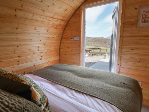 a bedroom with a bed in a wooden room with a window at Lili Wen Fach in Ruthin