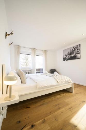 a white bedroom with a large bed and a window at Ferienwohnung MehrBlick in Garmisch-Partenkirchen