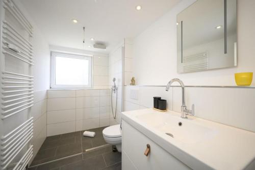 a white bathroom with a toilet and a sink at Ferienwohnung MehrBlick in Garmisch-Partenkirchen