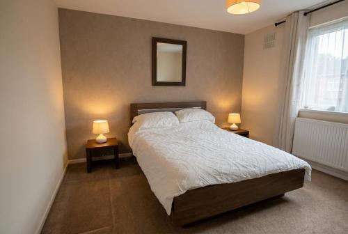 a bedroom with a bed with two lamps on two tables at Contemporary Private Home Near Nottingham with Free Parking and Garden in Sandiacre