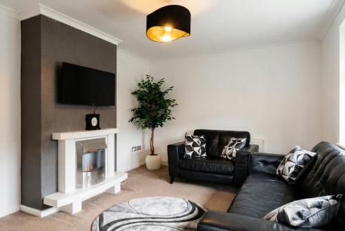 a living room with a black leather couch and a fireplace at Contemporary Private Home Near Nottingham with Free Parking and Garden in Sandiacre