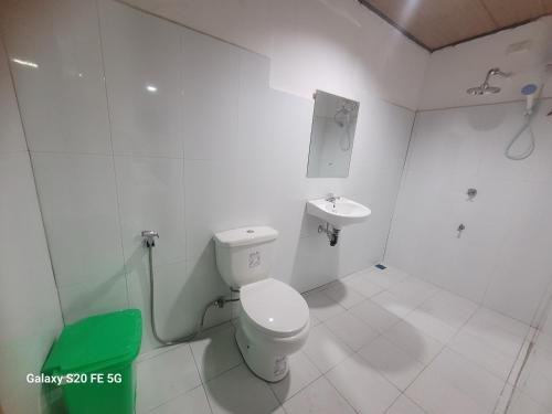 a white bathroom with a toilet and a sink at Knights-Apple Inn in Mambajao