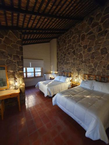 a bedroom with two beds and a stone wall at Sandy Shores Cabaña 4 in La Paz