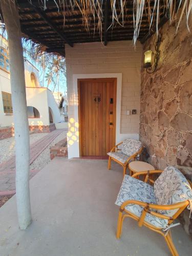 a porch with two chairs and a wooden door at Sandy Shores Cabaña 4 in La Paz