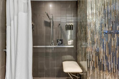 a bathroom with a shower with a bench and a shower curtain at Revere Hotel Boston Common in Boston