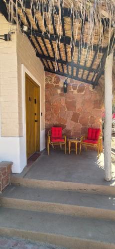 a patio with two red chairs and a brick wall at Sandy Shores Cabaña 8 in La Paz