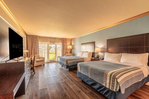 a hotel room with two beds and a flat screen tv at Safety Harbor Resort & Spa Trademark Collection by Wyndham in Safety Harbor