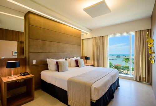 a bedroom with a large bed and a large window at Hotel Beira Mar in Fortaleza