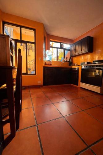 a kitchen with orange walls and a tiled floor at Casa Josvic in San Cristóbal de Las Casas