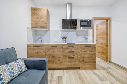 a kitchen with a sink and a couch in a room at Apartamentos Toril in Córdoba