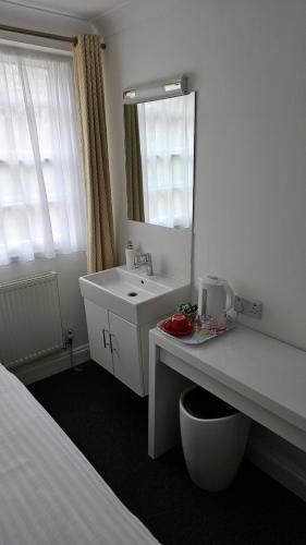 a white bathroom with a sink and a mirror at Hotel Meridiana in London