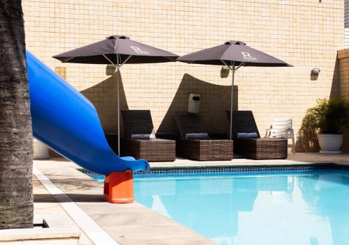 a blue slide next to a swimming pool with umbrellas at Riale Imperial Flamengo in Rio de Janeiro