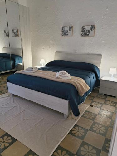 a bedroom with a bed with a blue blanket and a mirror at IN CENTRO apartments in Torre Maggiore
