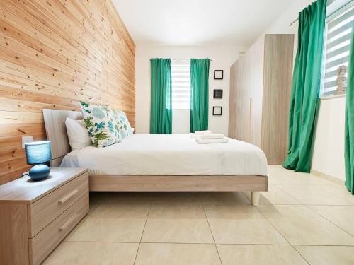a bedroom with a large bed with green curtains at Hilltop Retreat in Kalkara