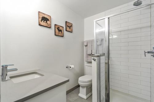 a white bathroom with a toilet and a sink at Spacious 1 Bed with Mountain Views only steps from Downtown in Canmore