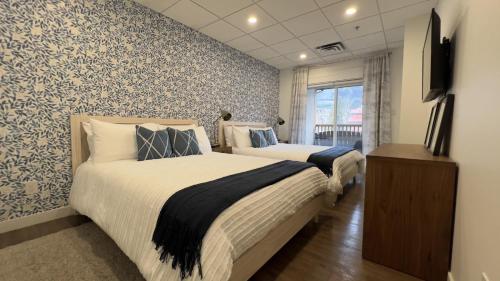 a bedroom with two beds and a television in it at Spacious 1 Bed with Mountain Views only steps from Downtown in Canmore