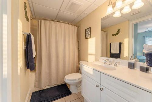 a bathroom with a toilet and a sink and a mirror at Goin Coastal Emerald Beach Unit 729 in Panama City Beach