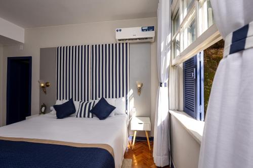 a bedroom with a bed with blue pillows and a window at Altos de Colombo Guest House Boutique - Soft Opening in Rio de Janeiro