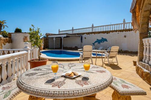 a patio with a table with two glasses of orange juice at Enjoy complete seclusion at Casa Delfin, featuring your own stunning private pool and sunset views in Gran Alacant