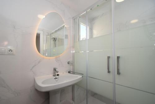 a white bathroom with a sink and a mirror at ADELFAS - Fincas Arena in Benidorm