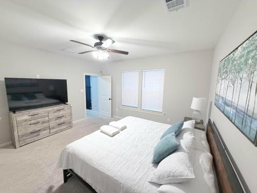 a white bedroom with a bed and a flat screen tv at Brand-new home close to LSU campus in Baton Rouge
