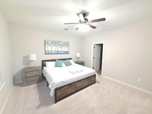 a white bedroom with a bed and a ceiling fan at Brand-new home close to LSU campus in Baton Rouge