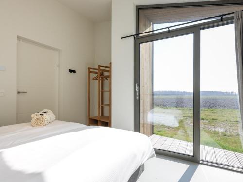a bedroom with a bed and a large window at Natuurhuis Houtkant in Wissenkerke