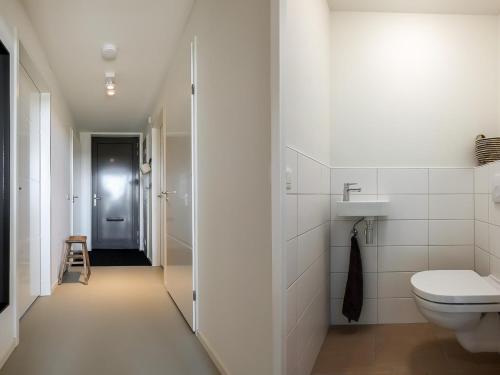a white bathroom with a toilet and a sink at Natuurhuis Houtkant in Wissenkerke