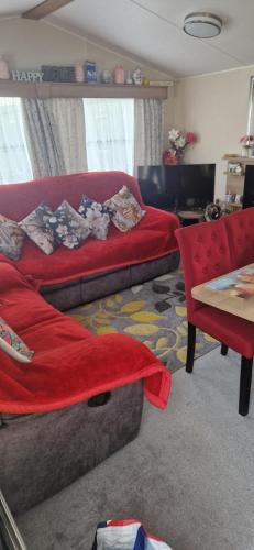 a living room with a red couch and a table at 128 Lido Beach in Prestatyn