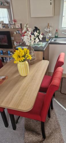 a wooden table with a vase of yellow flowers on it at 128 Lido Beach in Prestatyn