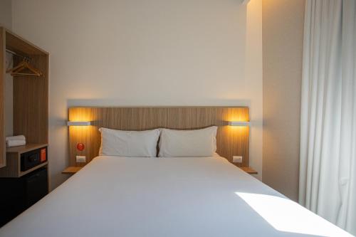 a bedroom with a large white bed with two pillows at Hotel Moov Curitiba in Curitiba