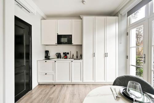 a white kitchen with white cabinets and a table at The Collection Stays Chelsea in London