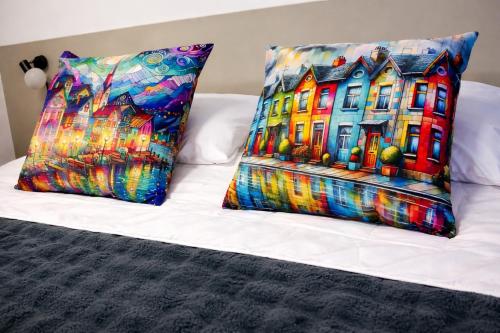 two pillows on a bed with a painting of a house at Aveiro Ria View in Aveiro