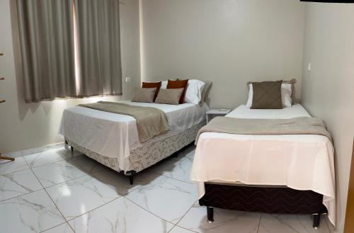 two beds in a room with white walls and marble floors at aconchego da serra in Coronel José Diaz